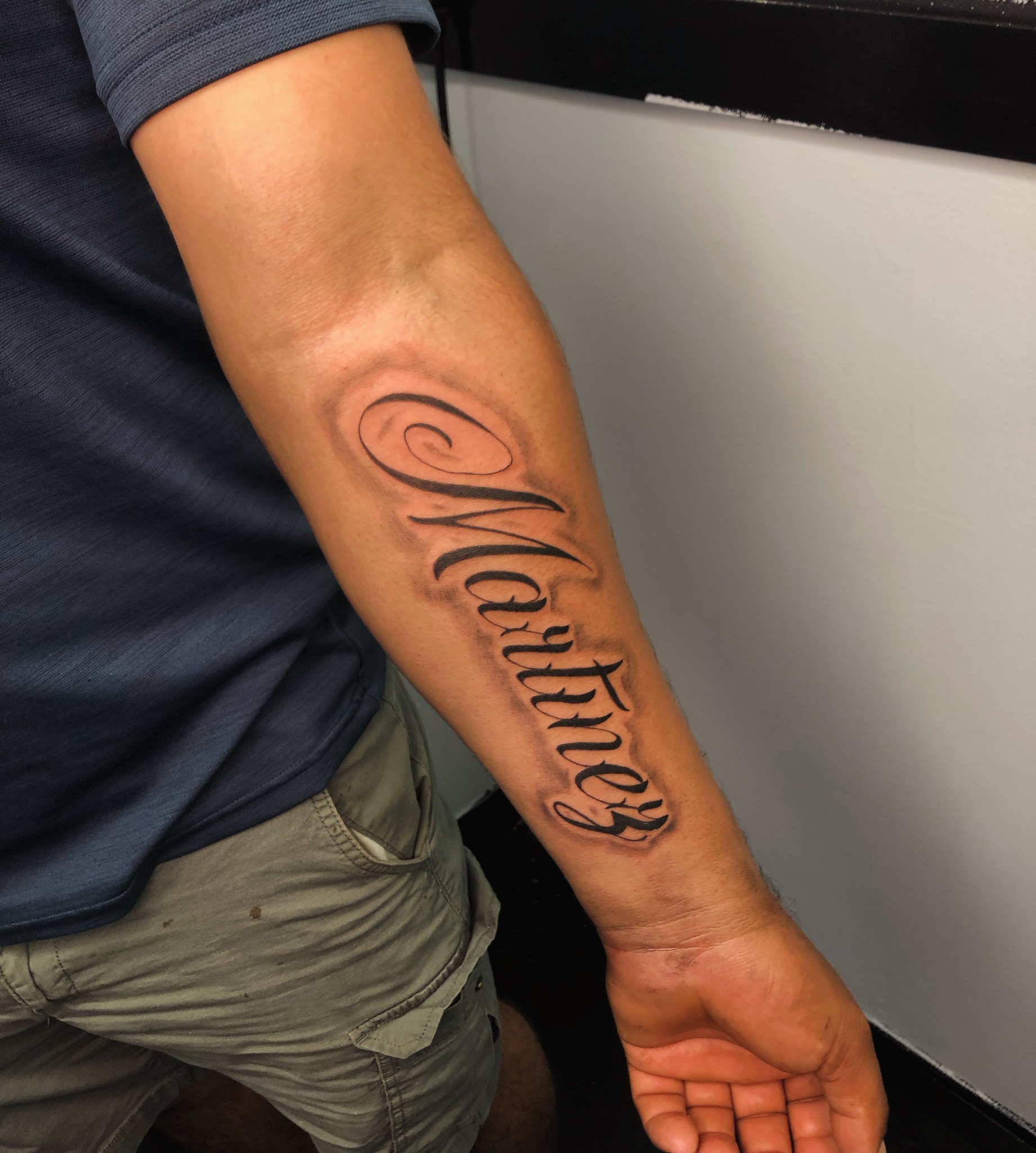 Black and grey script lettering forearm tattoo by Blady