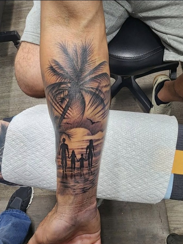 Black and grey palm tree and family sunset forearm tattoo by Miguel Ramos